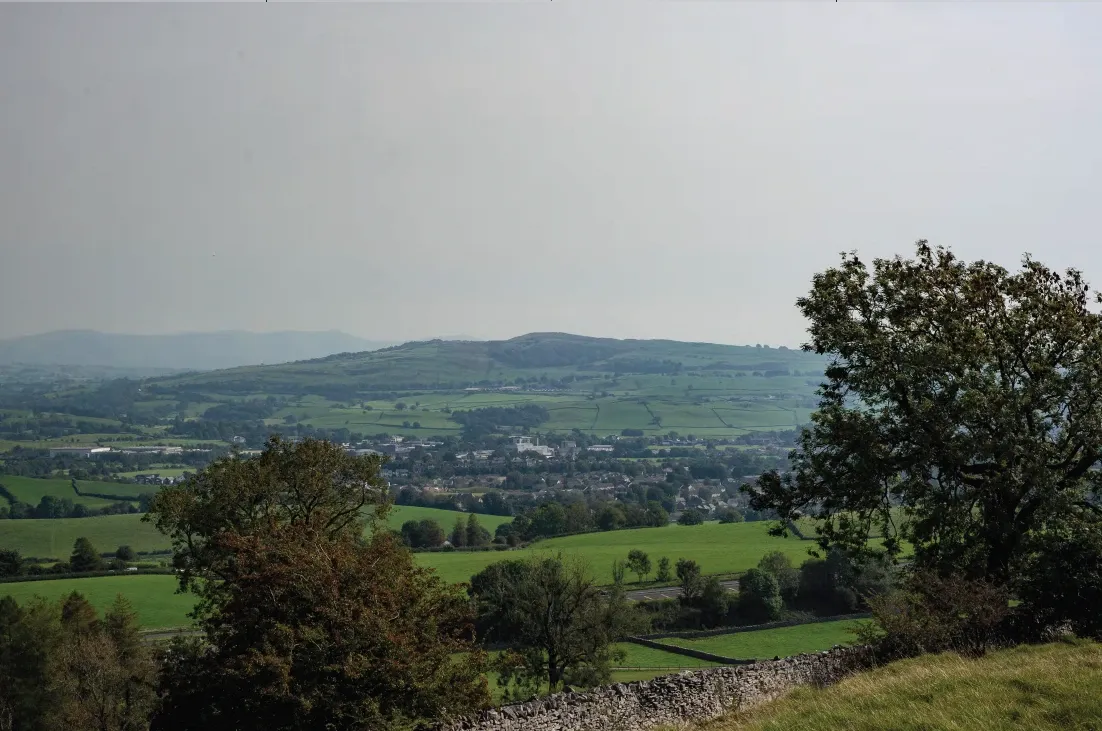Landscape setting viewed across fields and trees towards Kendal